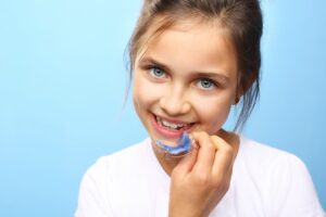 Young girl holding a blue Hawley retainer